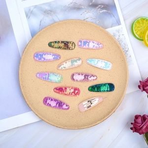 Close-up of assorted sequin hair clips in pastel colors on a round ceramic plate