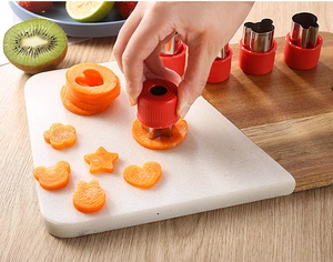 Macro shot of stainless steel fruit cutters creating flower shapes on a wooden board