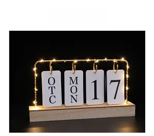 Close-up of wooden flip calendar with warm LED string lights on a black background