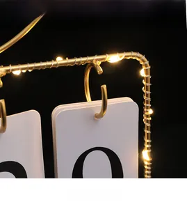 Detail of iron flip calendar with golden frame and warm LED string light decoration