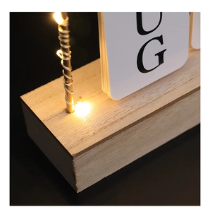 Detail of wooden desk calendar with warm LED string lights and minimalist flip cards