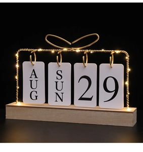 Detail of light wood calendar with gold iron frame, bow accent and warm LED fairy lights