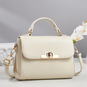 Detailed macro view of the cream leather texture and gold semicircular lock on this stylish bag