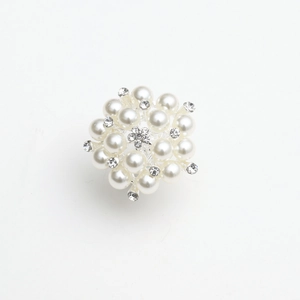 Detailed view of silver flower brooch with white faux pearls and clear rhinestones