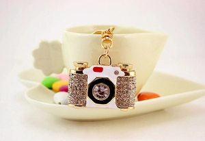 Detailed close-up of a sparkling crystal camera keychain hanging on a ceramic cup edge