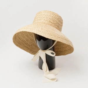 Macro shot of French cloche straw hat texture and elegant cream ribbon tie