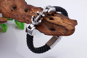 Detailed close-up of a men's anchor leather bracelet on a rustic wood element