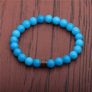 Detailed top view of beaded bracelet with light blue round beads on dark wood background