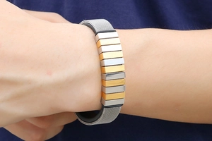 Detail eines gewebten Edelstahl-Mesh-Armbands mit abwechselnd gold- und silbernen Gliedern