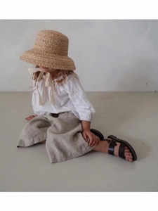 Detail of a kids French style raffia sun hat with white lace top and linen trousers
