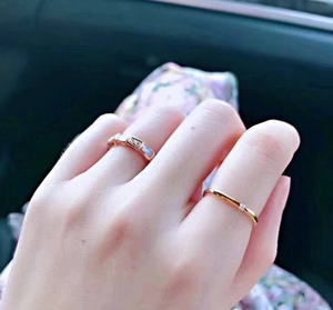 Close-up of stacked gold titanium square rings and minimalist diamond ring on hand