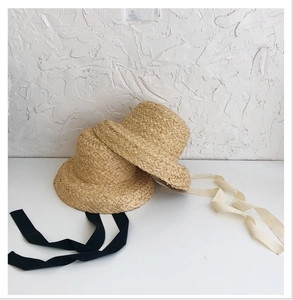 Detalle de sombreros de paja de rafia tejidos a mano con cintas largas negras y beige