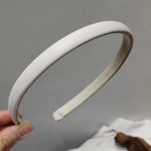 Detail of cream-white faux leather headband featuring a refined lychee grain texture