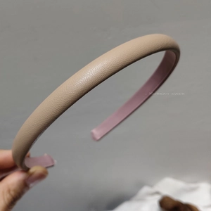 Detailansicht eines beigen Leder-Haarreifens mit Narbenstruktur und rosa Innenfutter