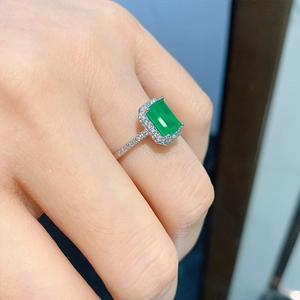 Emerald cut green gemstone ring with halo diamonds and pavé band shown on hand