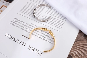 Detail of twisted open cuff bracelets in polished gold and silver on a fashion magazine