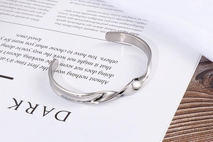 Detail shot of silver twisted metal cuff bracelet on a minimalist card with dark text