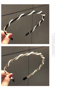 Detail of twisted faux pearl headbands in black and gold finish held by hand