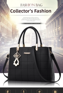 Detail of black pebbled leather handbag with square stitching and pearl charm