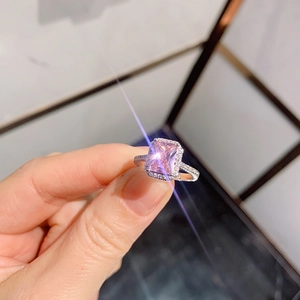 Close-up of a silver ring with a rectangular pink stone and halo diamond setting