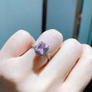 Macro shot of rectangular pink gemstone ring with halo diamonds on silver band