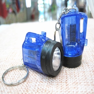 Macro detail of two blue transparent mini LED flashlight keychains with black rubber rings