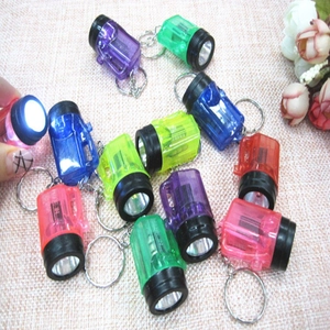 Mini LED flashlight keychains in assorted colors displayed on a woven fabric surface