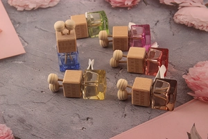 Flat lay of colorful square glass car perfume bottles with engraved wooden caps