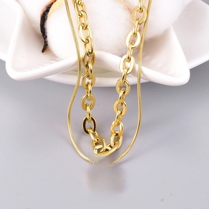 Macro shot of double-layered gold stainless steel necklace with engraved rectangle tag