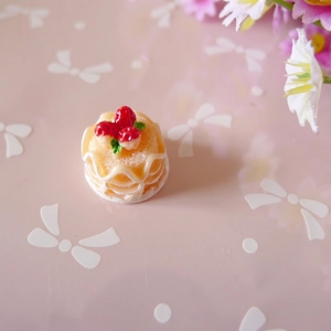 Macro detail of miniature strawberry cake charm with resin cream and red berries