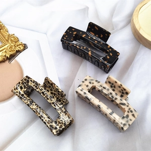 Three acetate hair claws in leopard and tortoiseshell patterns on a soft white cloth