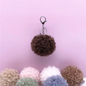 Close-up of soft curly faux fur plush ball keychain in multiple sweet pastel colors