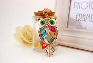Close-up of owl keychain with colorful crystals hanging on a decorative glass bottle