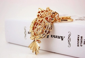 Macro detail of golden hollow owl keychain with sparkling diamonds and metal ring