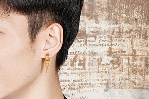 Vue détaillée de boucles d'oreilles triangulaires dorées portées sur fond vintage
