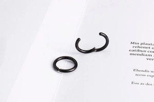 Macro detail of black stainless steel clip-on hoop earrings with a smooth hinge design