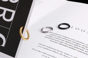 Detailed view of silver, gold and black stainless steel clip-on earrings on a book
