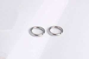 Close-up of a pair of minimalist silver-tone stainless steel hoop earrings on a white background
