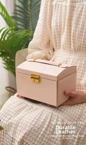 Detail of pink leather jewelry box with golden lock and handle held by a model