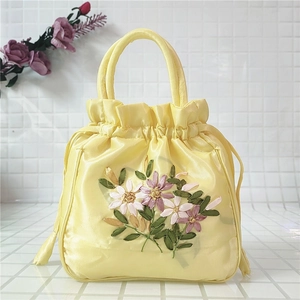 Détail d'un sac seau en satin jaune avec broderie de rubans délicate et cordon
