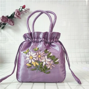 Close-up of lavender satin drawstring bag with detailed ribbon floral embroidery