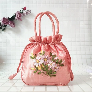 Detailed embroidery on pink satin bucket bag with floral patterns and drawstring closure