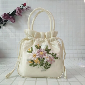 Detail of elegant cream satin drawstring handbag with colorful 3D ribbon flower embroidery