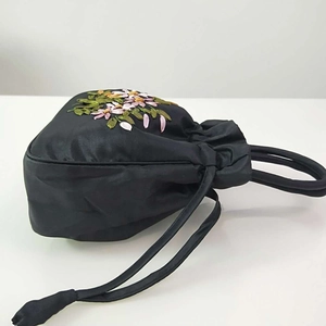 Detail of floral embroidery on black satin drawstring bucket bag with traditional style