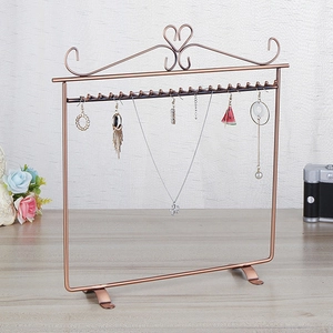 Detail of bronze metal jewelry stand with heart decor and hooks for necklaces