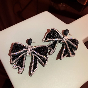 Close-up of black bow earrings with sparkling white crystals and silver needle studs