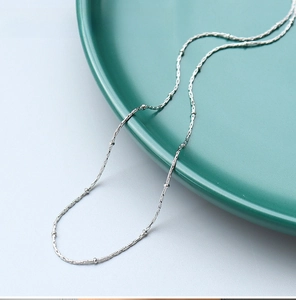 Close-up of 1mm stainless steel ball station chain on a green ceramic tray