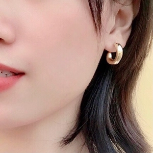 Close-up of model wearing chunky 18k gold plated stainless steel C-shape hoop earrings