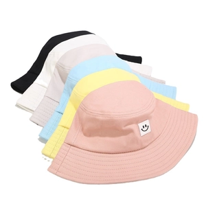Colorful cotton bucket hats with smiley face patch in pink, blue, yellow, and beige colors