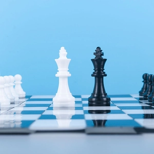 Close-up of glossy black and white resin chess pieces on a reflective board surface